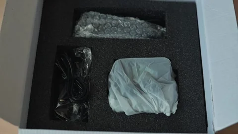 Hands unpack items from black foam inside a box. The process takes place at a Видео 344440615
