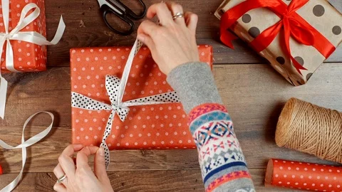 Hands unpacking present. Opening wrapped red gift box with ribbon and bow. Stock Footage 117189741