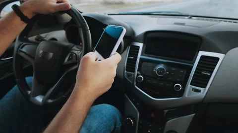 Hands of unrecognizable man driver using mobile phone while driving car, slow Stock Footage 231800984