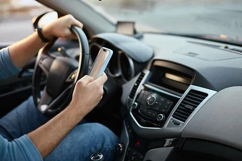 Hands of unrecognizable man driver using mobile phone while driving Stock Photos