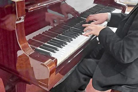 Hands of an unrecognizable pianist of man in classical suit playing an old gr Stock Photos