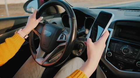 Hands of unrecognizable woman driver using mobile phone while driving car, slow Stock Footage 231801400