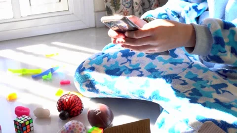 Hands of unrecognized kid in soft pajama sitting on floor surrounded by color Stock Footage 167141660
