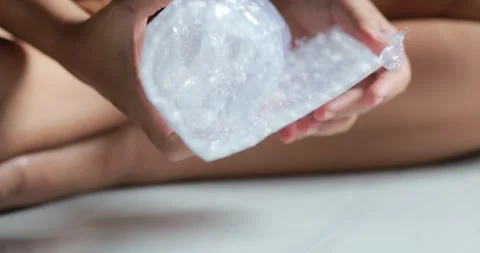 Hands unwrapping bubble wrap from a clear glass after packaging, unpacking,.. Stock Footage 341768319