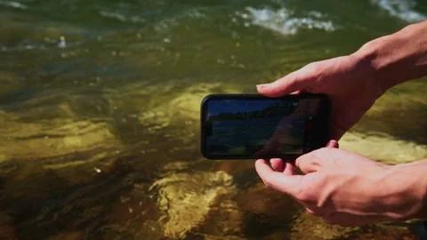 Hands use device to film river Stock Footage 334162360