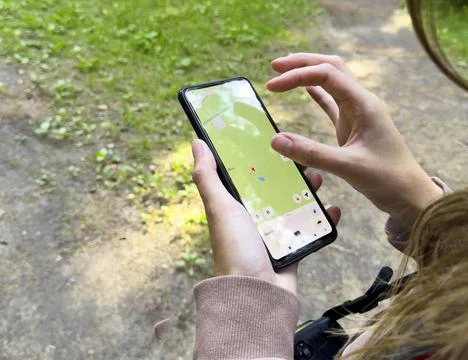 Hands use smartphone map application in outdoor setting. Person navigates f.. Stock Photos