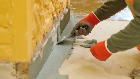 Hands use a spatula to putty the protrusion of the wall with the floor. Video stock 199837608