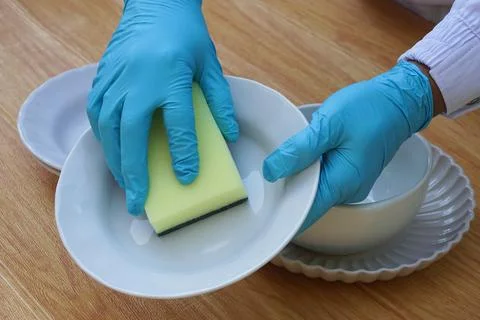 Hands use sponge scrubber to clean dish. Stock Photos