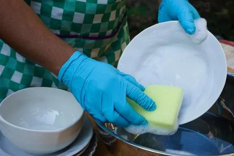 Hands use sponge scrubber to clean dish. Stock Photos