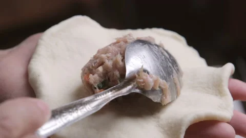 Hands use a spoon to scoop the marinated minced pork on dough to make buns. Stock Footage 167781688