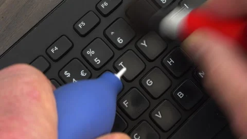 Hands using a blower and brush to clean a dirty computer keyboard. Video stock 248130679