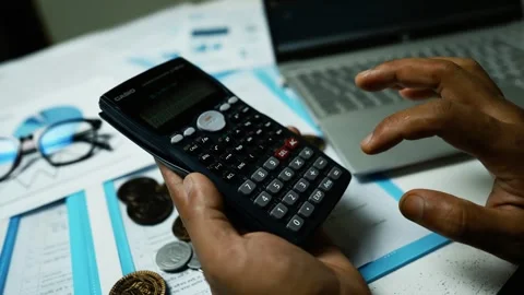 Hands Using Calculator with Financial Documents, Close-up of hands using a .. Видео 304960910