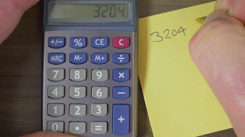 Hands using a calculator then writing down the result. Stock Footage 139444499