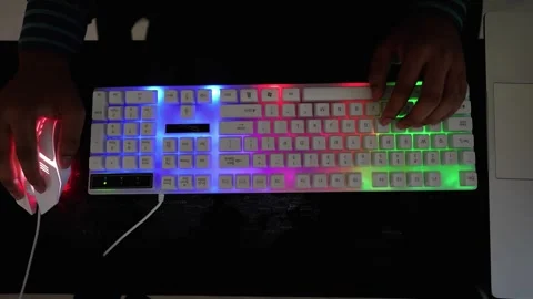 Hands using a colorful RGB backlit keyboard and mouse on a dark surface Stock Footage 318056665