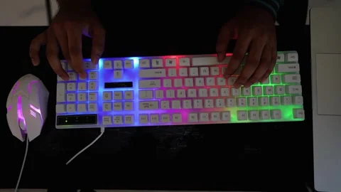 Hands using a colorful RGB backlit keyboard and mouse on a dark surface Stock Footage 318056671