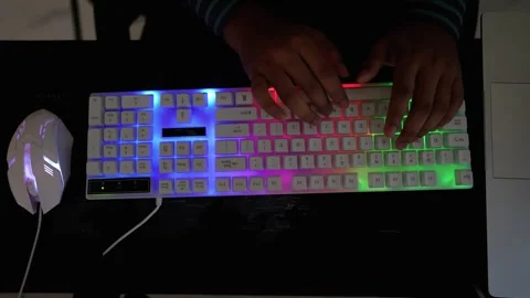 Hands using a colorful RGB backlit keyboard and mouse on a dark surface Stock Footage 318056676