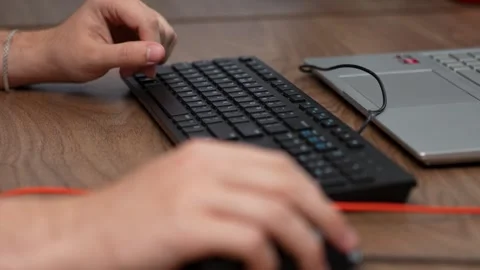 Hands using computer keyboard and a mouse at a wooden desk, close-up Stock Footage 321284956