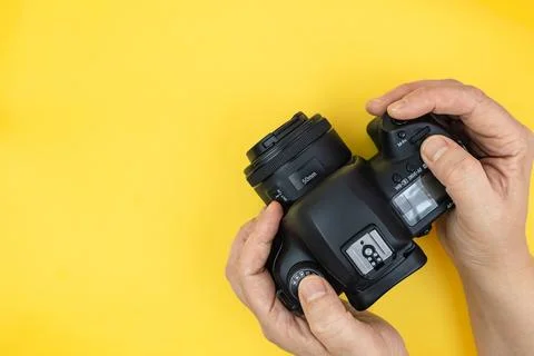 Hands using digital camera on a yellow background with copy space. Top view.. Stock Photos
