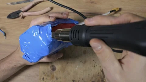 Hands using heat gun to seal blue shrink wrap on lithium battery pack 스톡 동영상 329677945