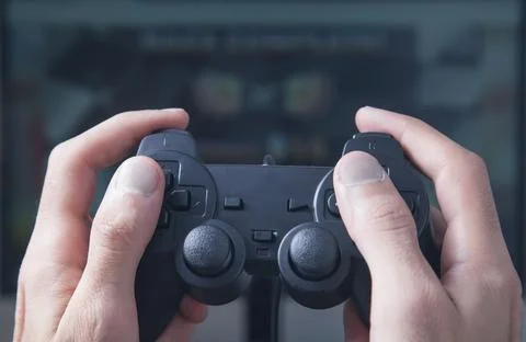 Hands using joystick. Playing video game on computer monitor Stock Photos