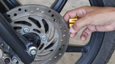 Hands using key of disc brake lock at front wheel on motorcycle Stock Footage 145716585