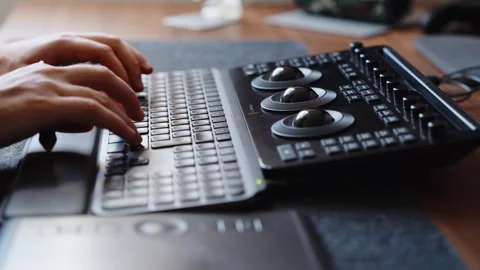 Hands Using Keyboard and Color Grading Control Panel in Modern Editing Studio Stock Footage 345691966
