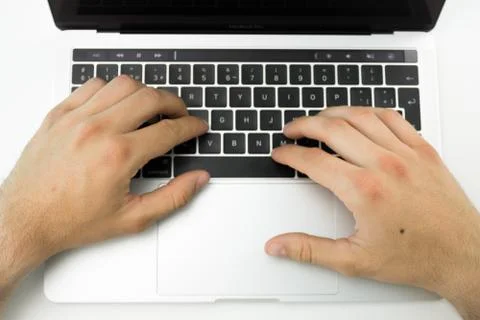 Hands using the keyboard and touchpad of a laptop computer on a white table. Stock Photos