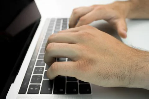 Hands using the keyboard and touchpad of a laptop computer on a white table. Stock Photos