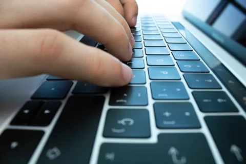 Hands using the keyboard and touchpad of a laptop computer on a white table. Stock Photos