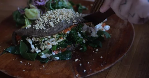 Hands using knife and fork cut creamy vegan calzone Stock Footage 282968536