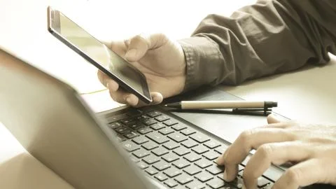 Hands using laptop and smartphone for online shopping with daytime soft lig.. Stock Photos