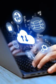 Hands using a laptop with cloud computing icons in a dark setting Foto stock