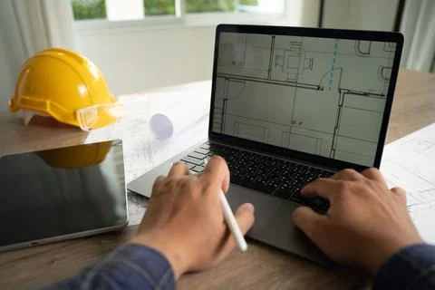 Hands using laptop displaying architectural blueprint with stylus and devic.. Stockfoto's