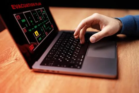 Hands using a laptop to review an emergency evacuation plan on a computer Stock Photos