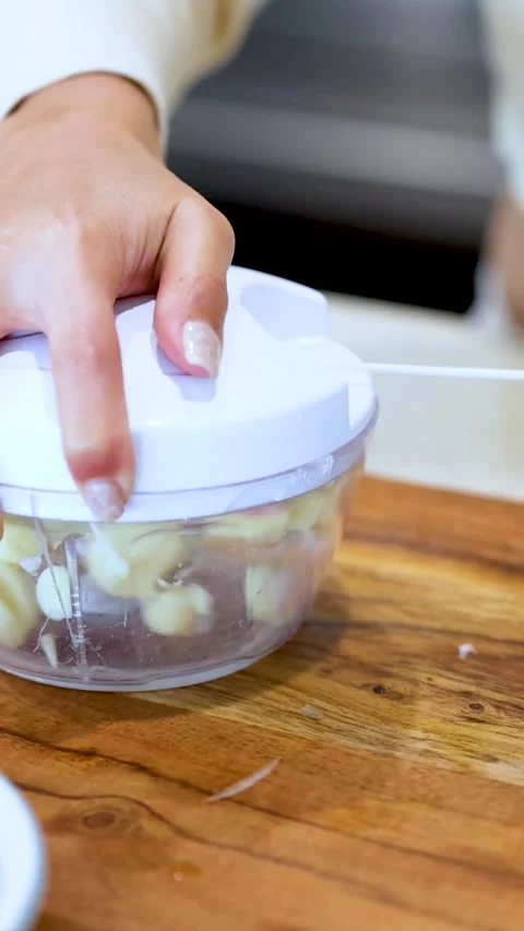 Hands Using Manual Pull String Food Chopper to Mince Garlic Stock Footage 329606277