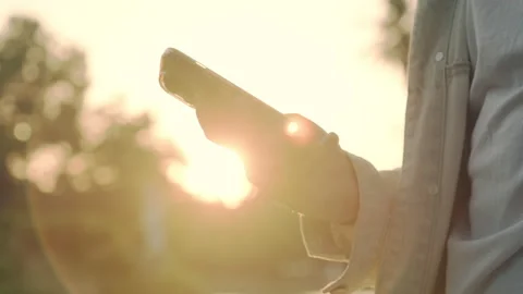 Hands using mobile over sunset. Close-up of men's hands with a mobile in th.. Stock Footage 254657434