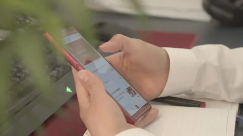 Hands Using Red Smartphone at Office Desk with Plants Vídeos de archivo 334857903