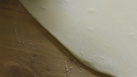 Hands Using Rolling Pin to Flatten Dough on Table Dusted with Flour Stock Footage 288817364