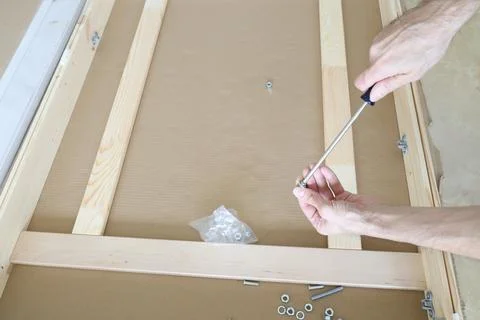 Hands Using Screwdriver to Tighten Bolt in Wooden Furniture Frame DIY Assembly C 写真素材