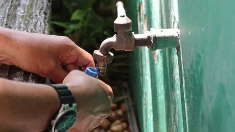 Hands using screwdriver tighten clamp with rubber hose to the metal faucet Stock Footage 147139377