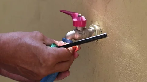 Hands using screwdriver tighten clamp with rubber hose to the metal faucet Stock Footage 147140410