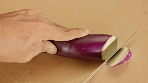 Hands using sharp knife slicing fresh purple eggplant into round pieces on .. Stock Footage 324820089