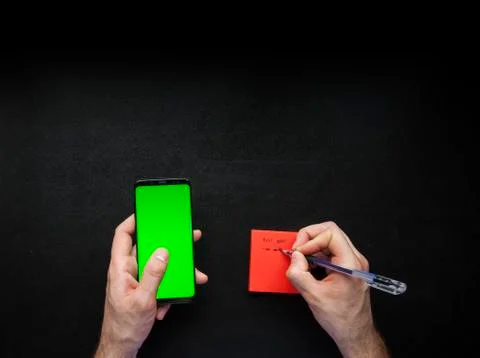 Hands using smart phone and noting down on sticky notes Stock Photos