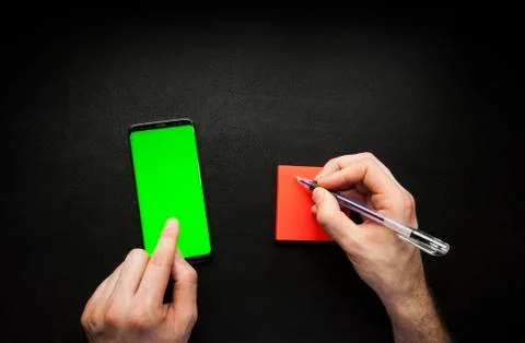 Hands using smart phone with green screen and noting down Stock Photos