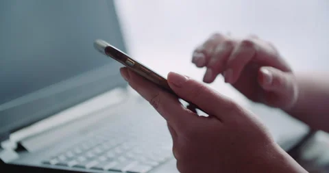 Hands Using Smartphone Above Laptop Keyboard at Desk Vídeos de archivo 336469511