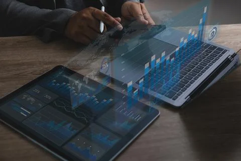 Hands using smartphone beside laptop and tablet with digital charts, analyz.. Stock Photos