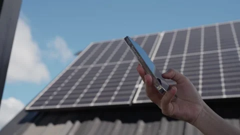 Hands using smartphone to control electricity usage with solar panels on rooftop Stock-Footage 326085204