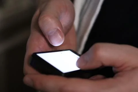 Hands using smartphone in dark indoor setting while engaging with digital c.. Stock Photos
