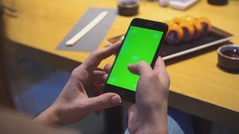 Hands using smartphone with green screen sushi rolls background Vídeos de archivo 333835606