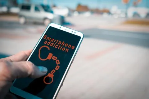 Hands using a smartphone with handcuffs and smartphone addiction words on screen Stock Photos